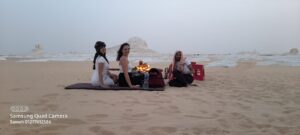 European tourists enjoying a luxury sunset picnic with fresh fruits during Private desert tours Egypt in the White Desert.